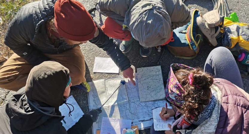 a group of people examine a map that is spread out on the ground